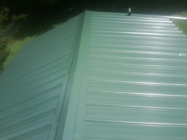 New green metal panels meeting at the ridge of a roof — Flat Roof Repair work by our crew in Corrales