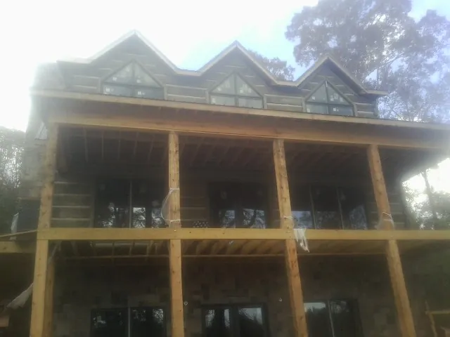 Dormers and porch framing on a large log home under construction — Roof Coating work by our crew in Corrales