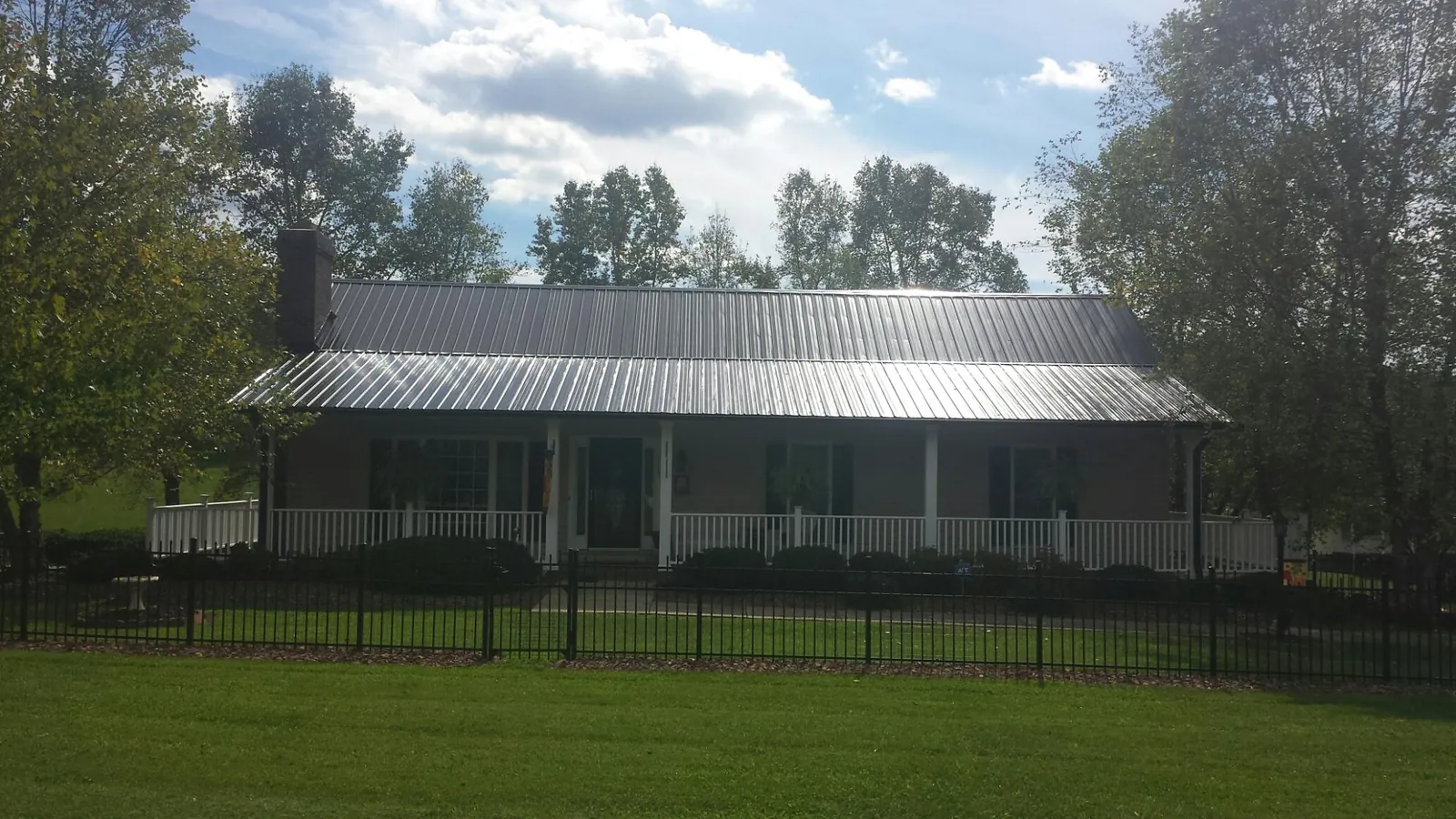 Gray metal roof on a brick ranch with a full width front porch — Gutter Guard Installation work by our crew in Corrales