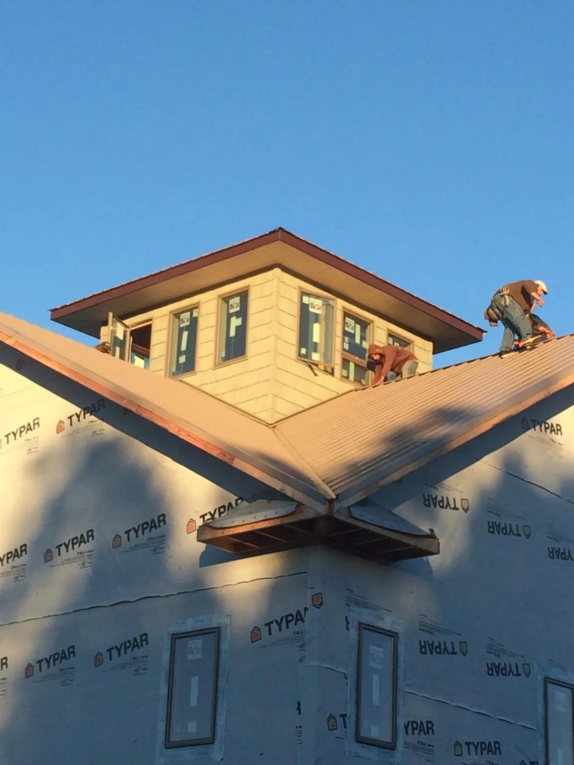 Roofers working around a rooftop cupola on a new metal roof at sunset — Roof Waterproofing in Corrales by Roofing Brothers